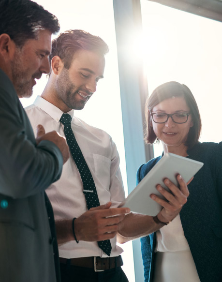 3 office workers looking over an electronic device
